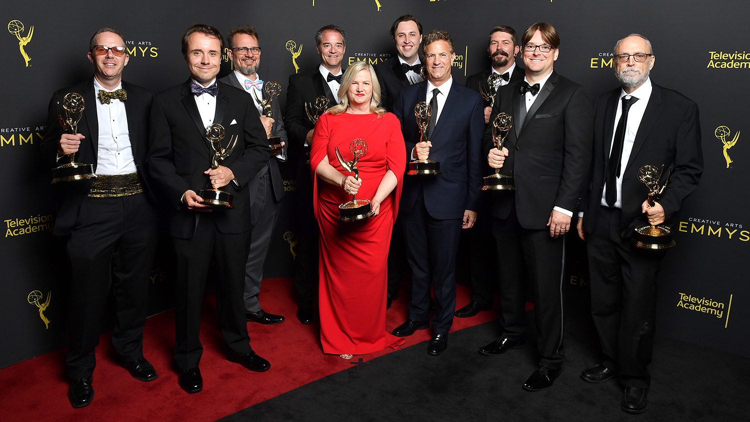 A group of people pose for a group photo holding Emmy Awards.