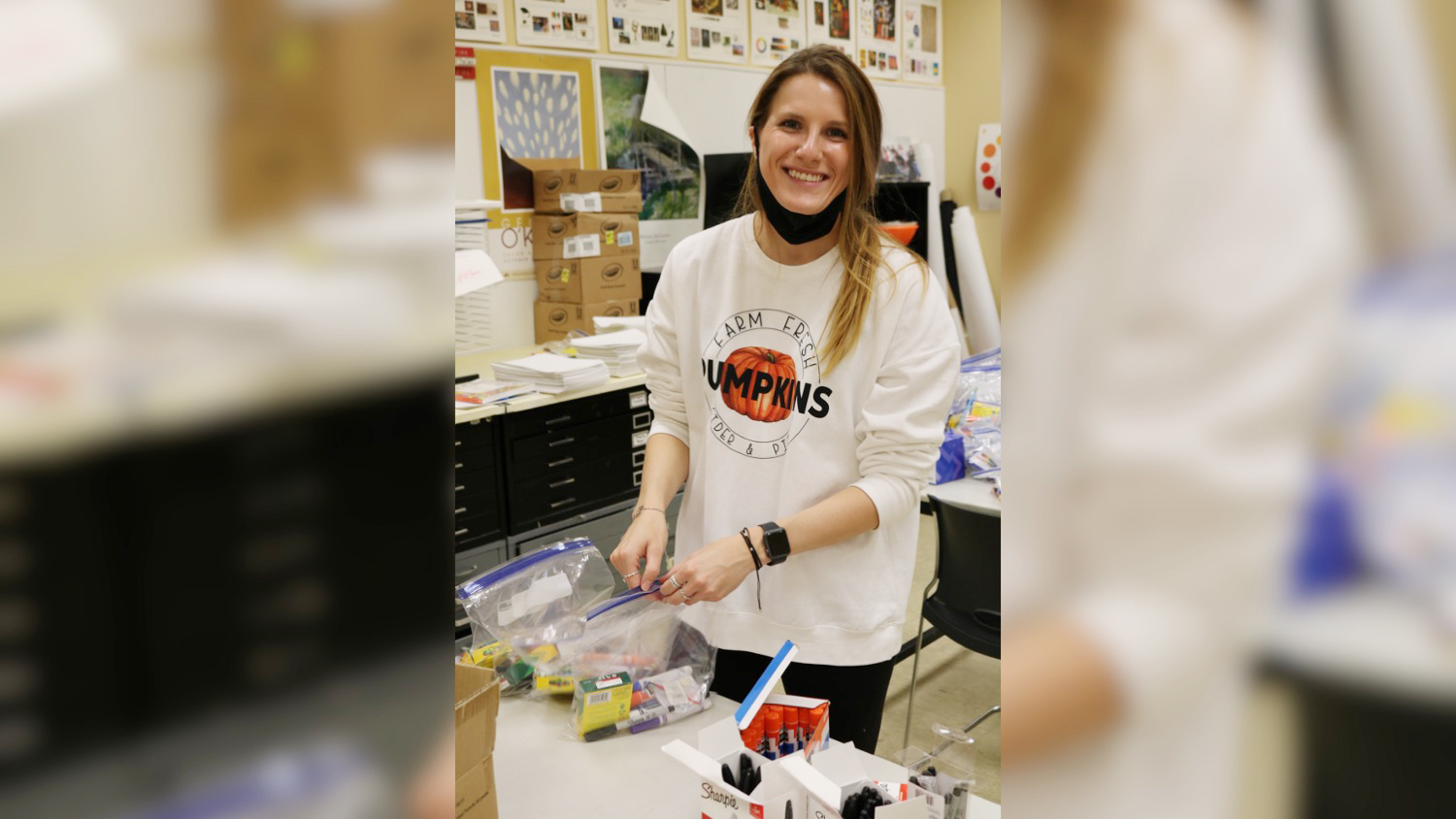 A student puts art supplies in a bag for a community outreach project.