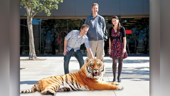 Three alumni stand next to a computer-generated tiger.