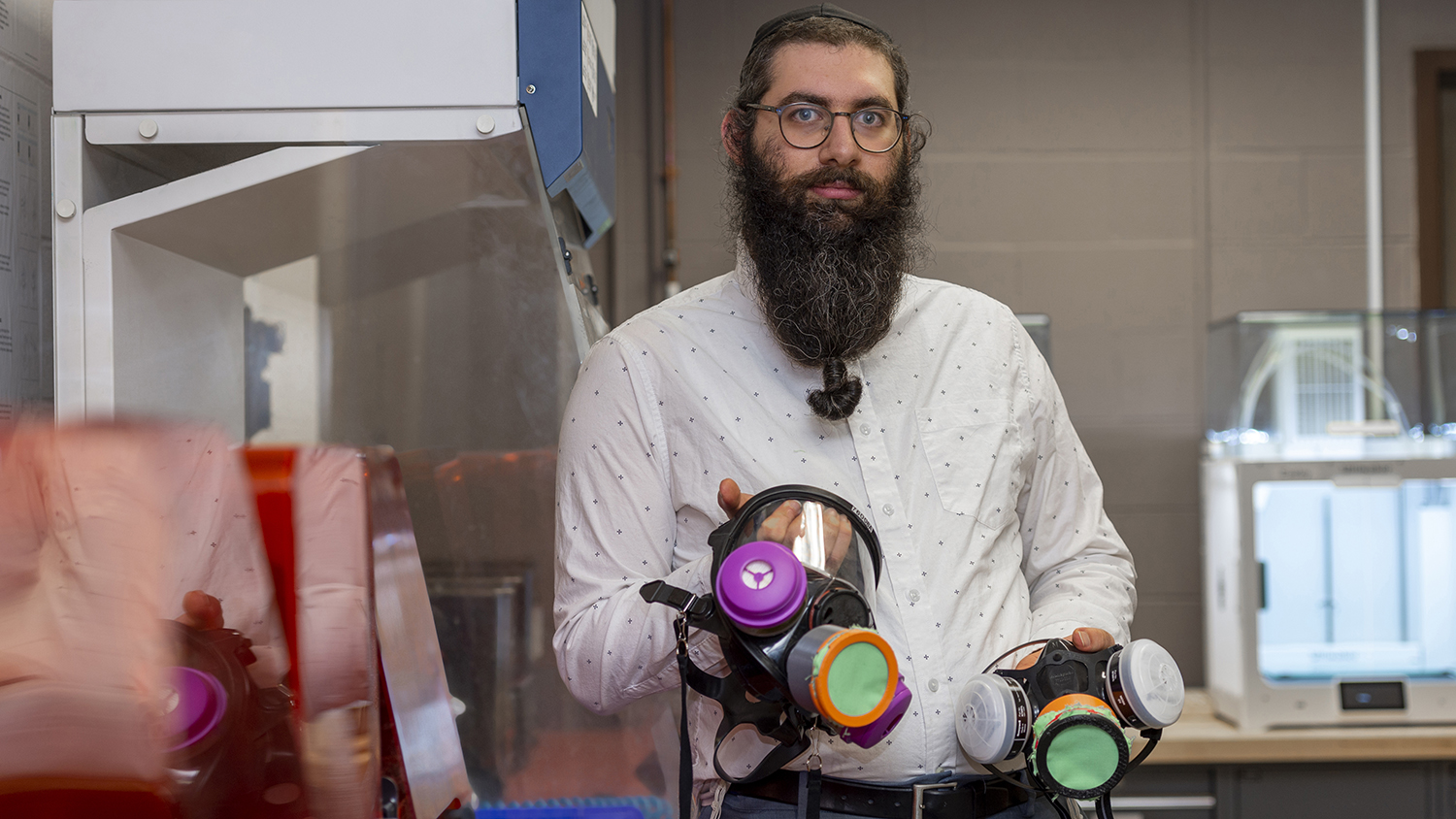 A portrait of Dan Gabber in the Fab Lab, holding respirator valves he 3D-printed.