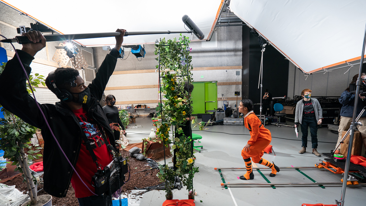 A student holds sound recording equipment over an actor.