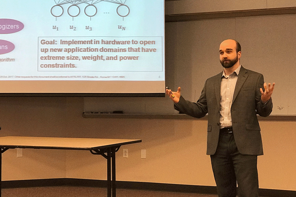 A professor teaching at the front of a classroom.