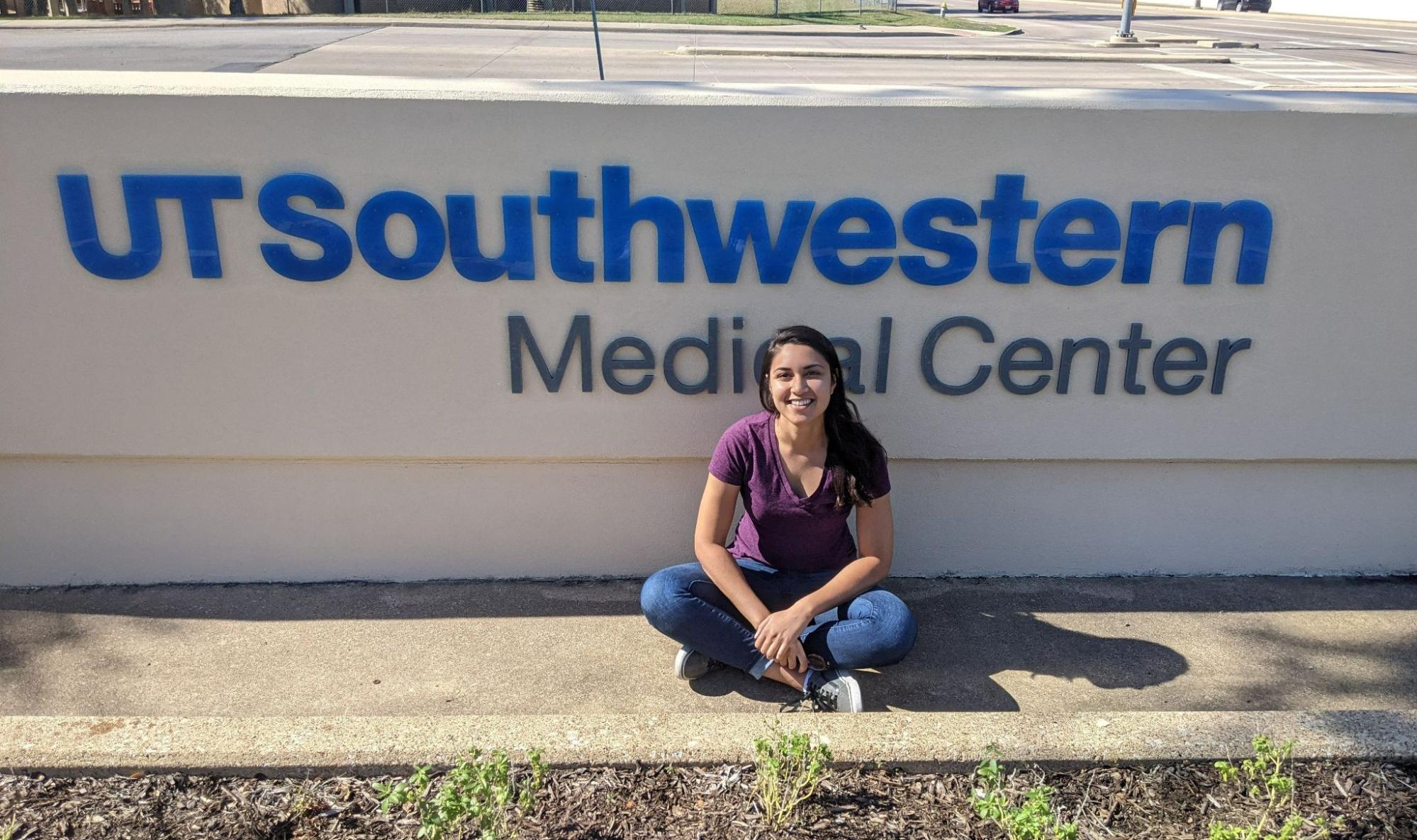 Kubra Naqvi sitting in front of the UT Southwestern sign