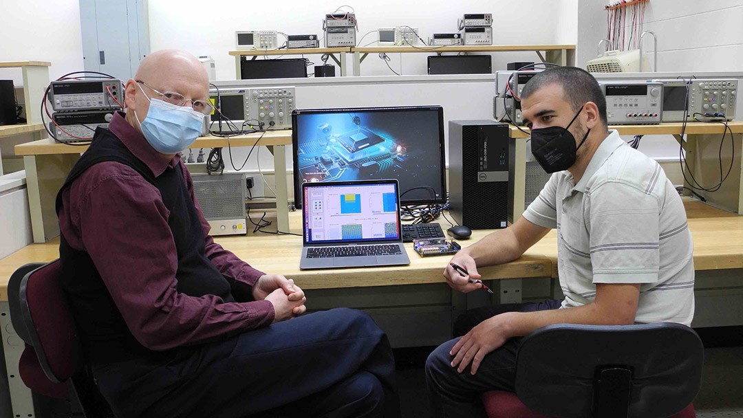 Professor Dorin Patru sitting at a lab desk with a student sitting on the right.