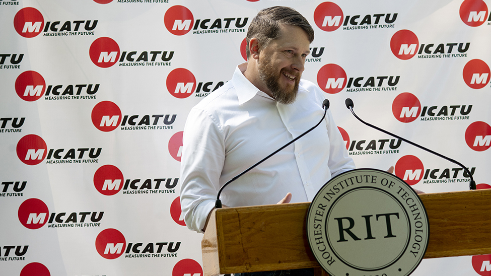 Founder and CEO of Micatu, Michael Oshetski standing at a podium with a microphone.