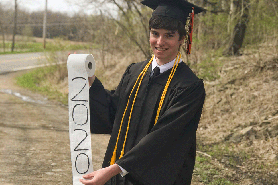 Jonah Sharp dress in commencement regalia and holding a roll of toilet paper that says 2020.