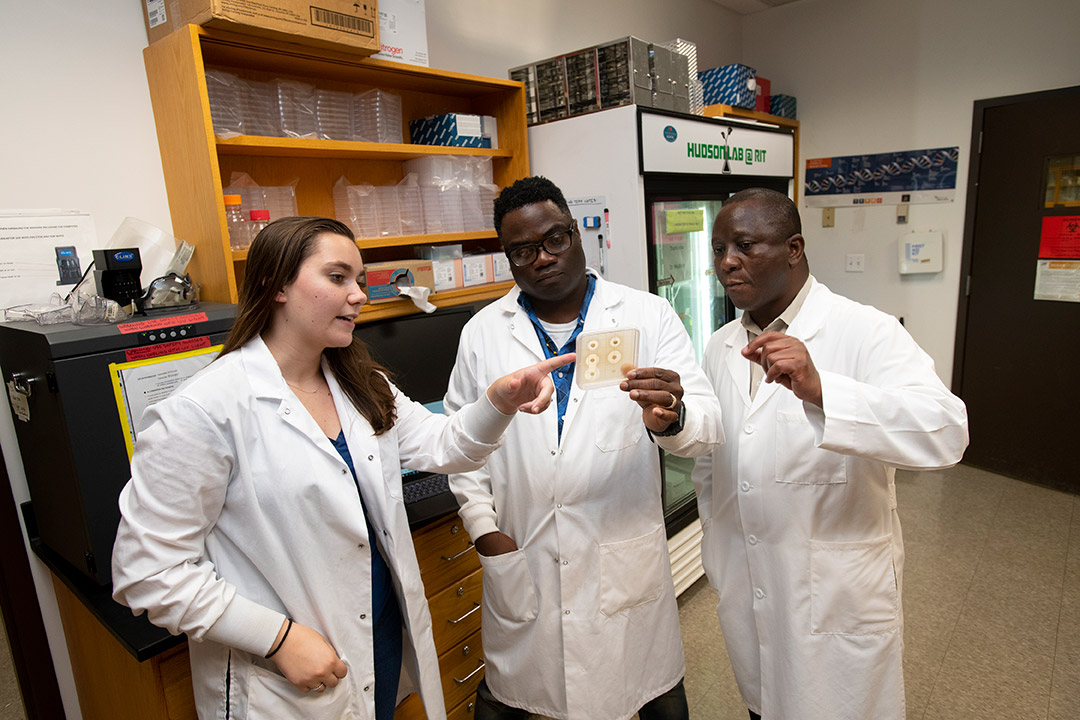 Marissa Schroeter confers with her mentors, RIT professors Andre Hudson and Bolaji Thomas, in an RIT lab to study bacteria from Lake Ontario.