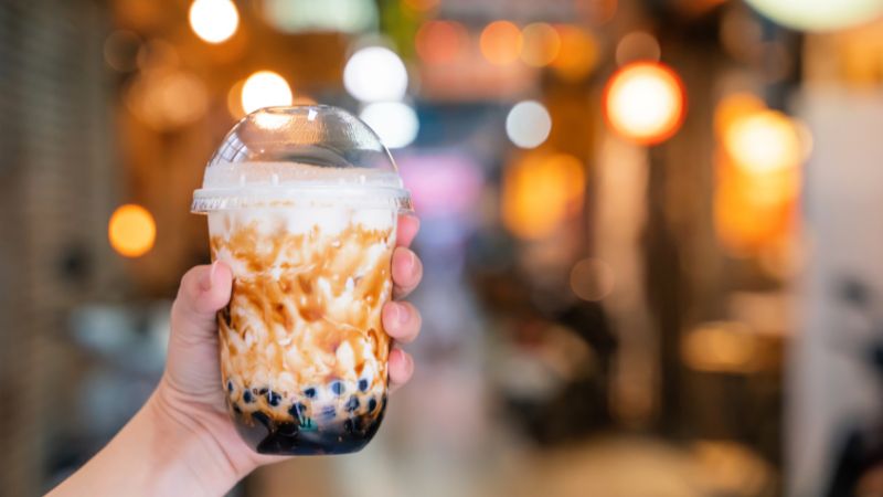 a person's hand holding a cup of bubble tea