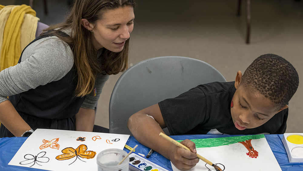 An MST candidate helps an RCSD student create artwork.