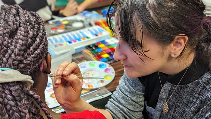 An MST student paints on the face of an RSCD student.