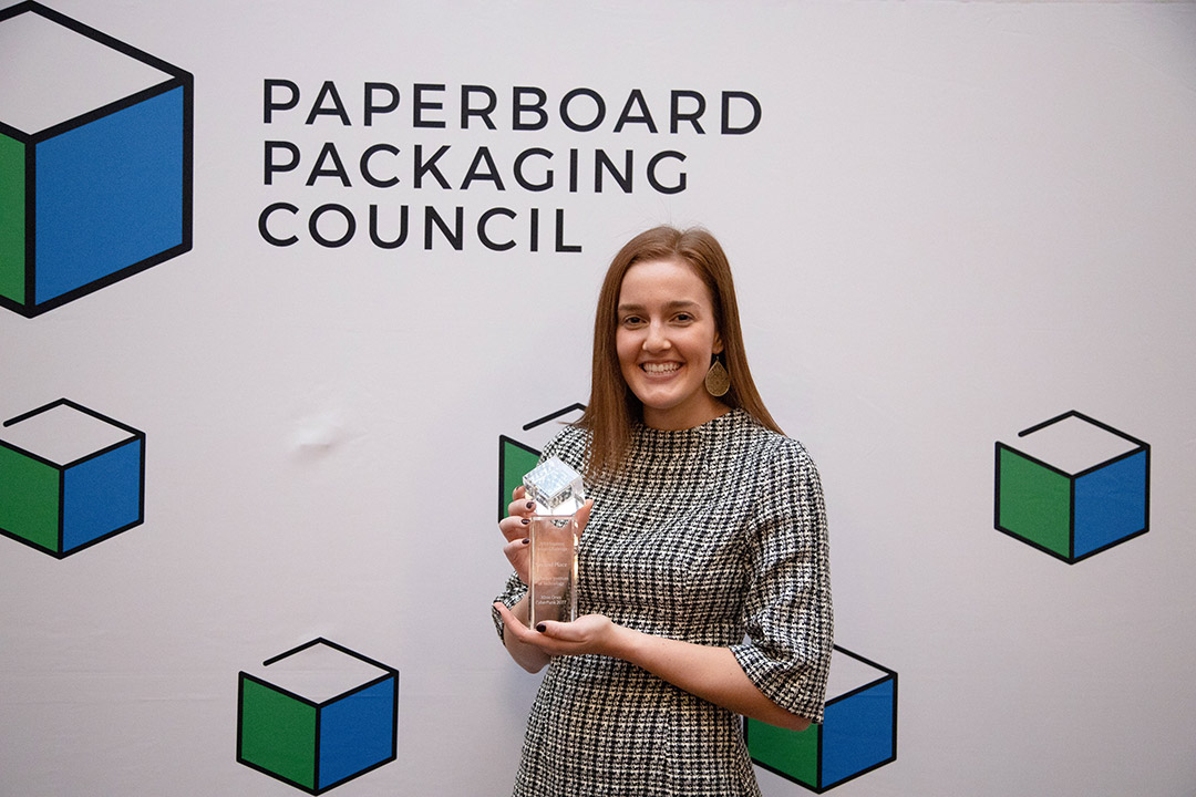 Kelly Fellner holding trophy at Paperboard Packaging Council Awards.