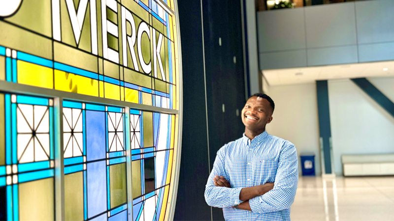 Nnamdi Akporji standing in front of a Merck sign