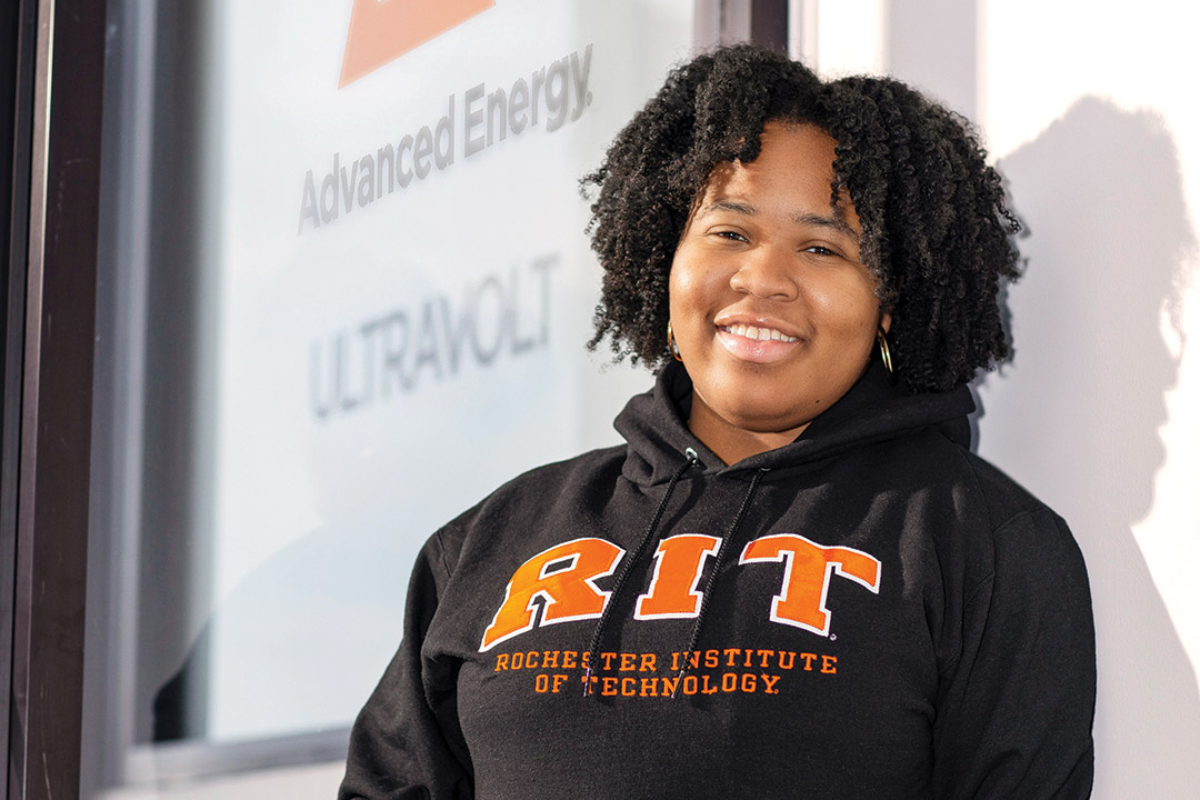 Elissa Sainthil, a microelectronic engineering major, stands before a PowerPoint presentation where she speaks about her co-op experience at Advanced Energy.