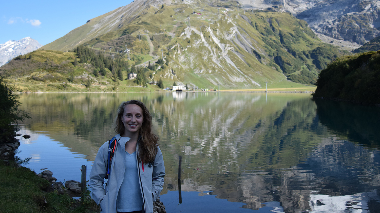 Alumna Victoria Scholl in front of a lake and mountain in Switzerland.