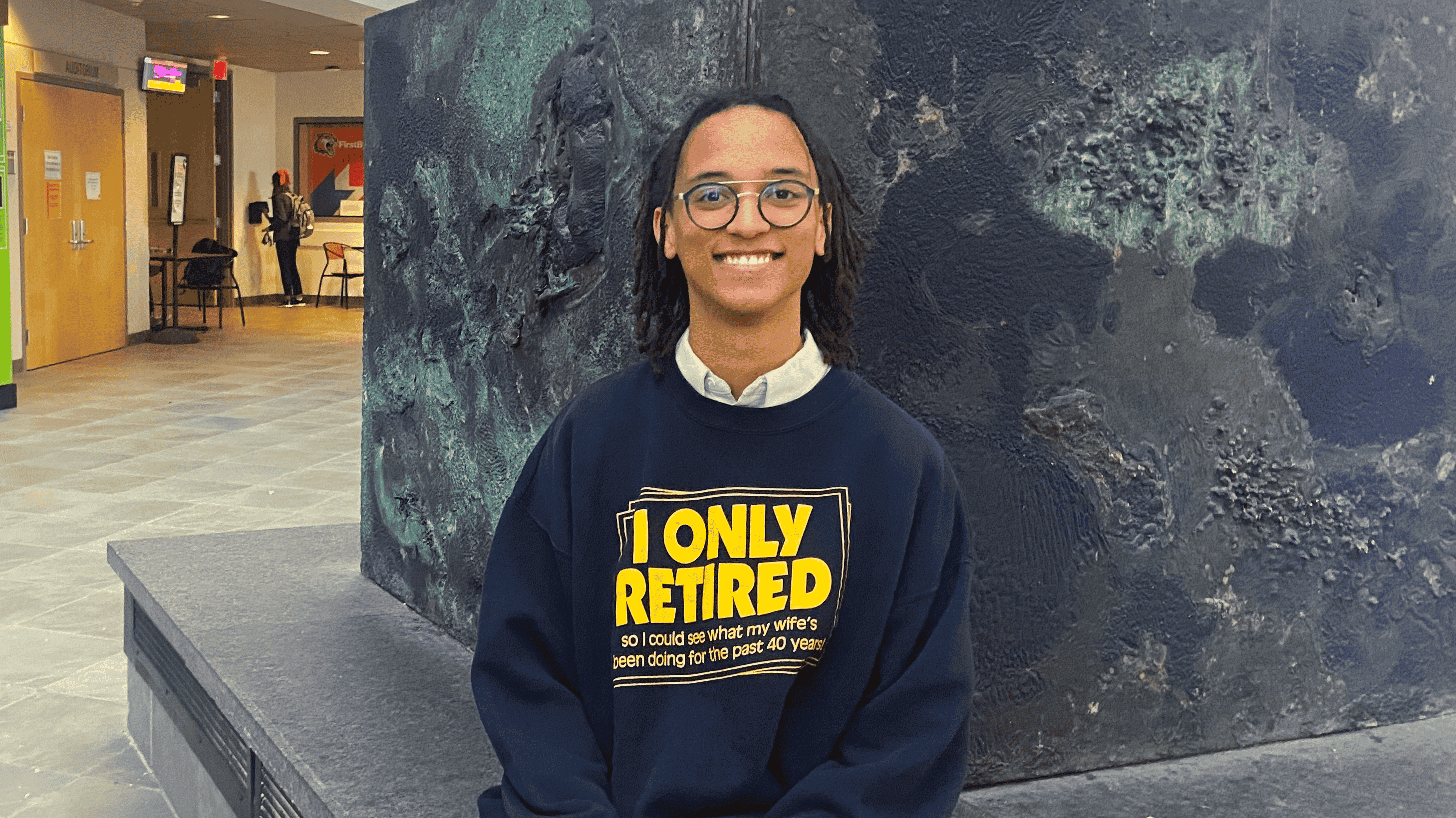 sejjemba sits in the golisano hall atrium smiling at the camera