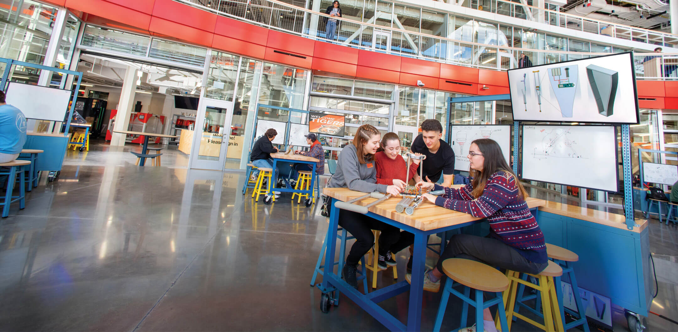 Several students sit aroound a table in the SHED makerspaces.