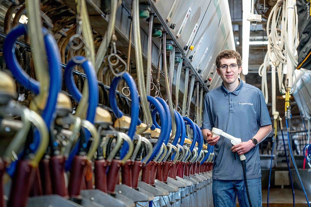 Jayden Neal stands next to dairy processing equipment in a barn on his family' farm.