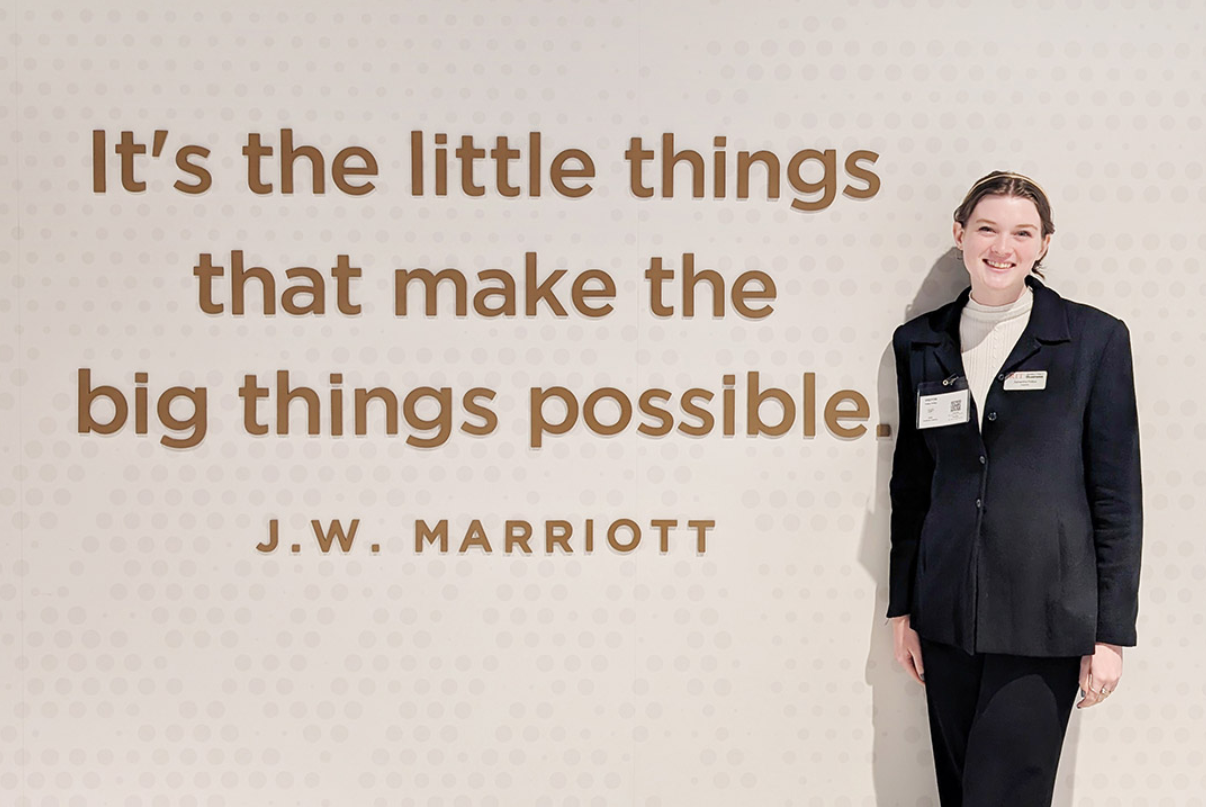 Hospitality student standing in front of J.W. Marriot sign