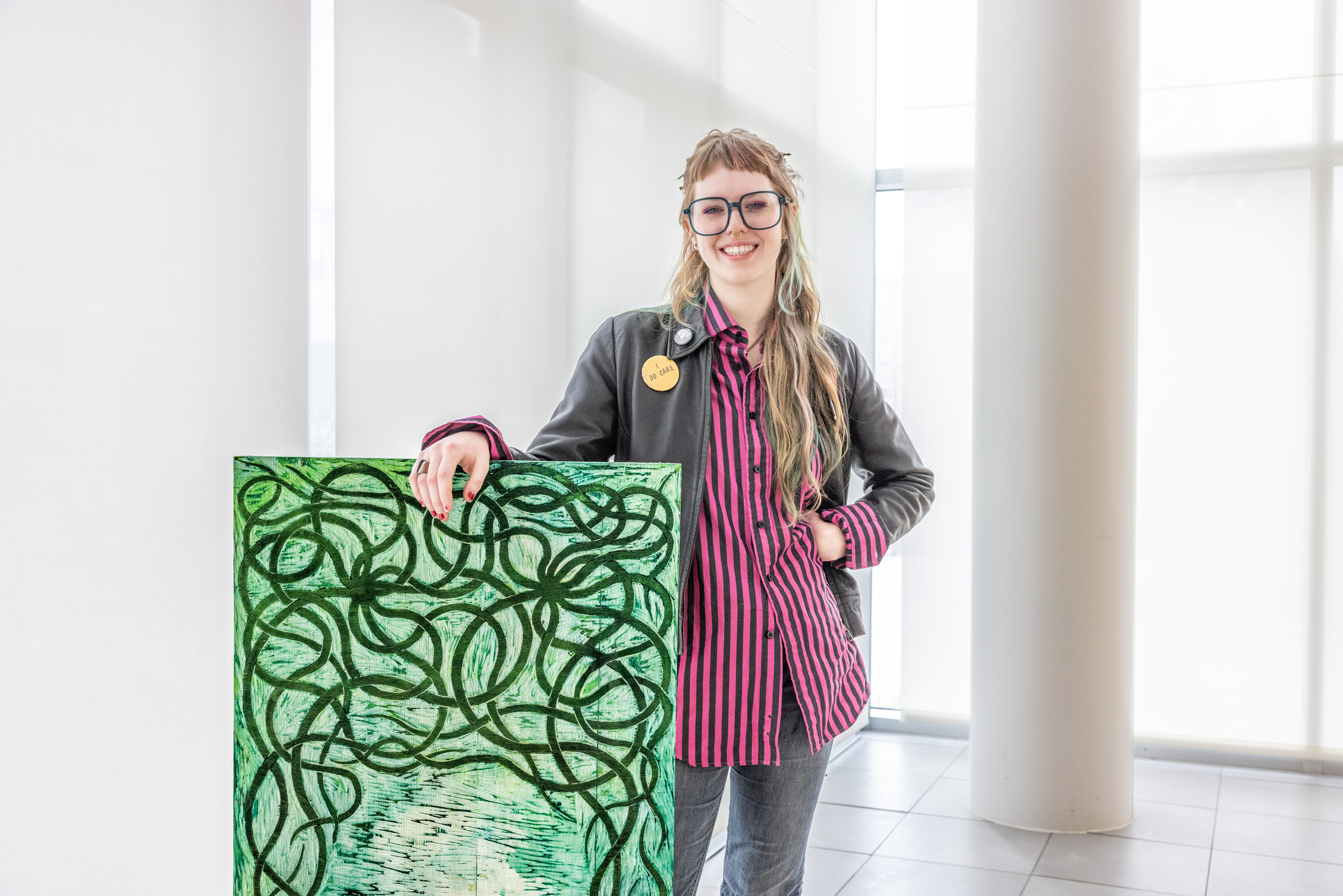 A young woman standing in front of a green hued canvas