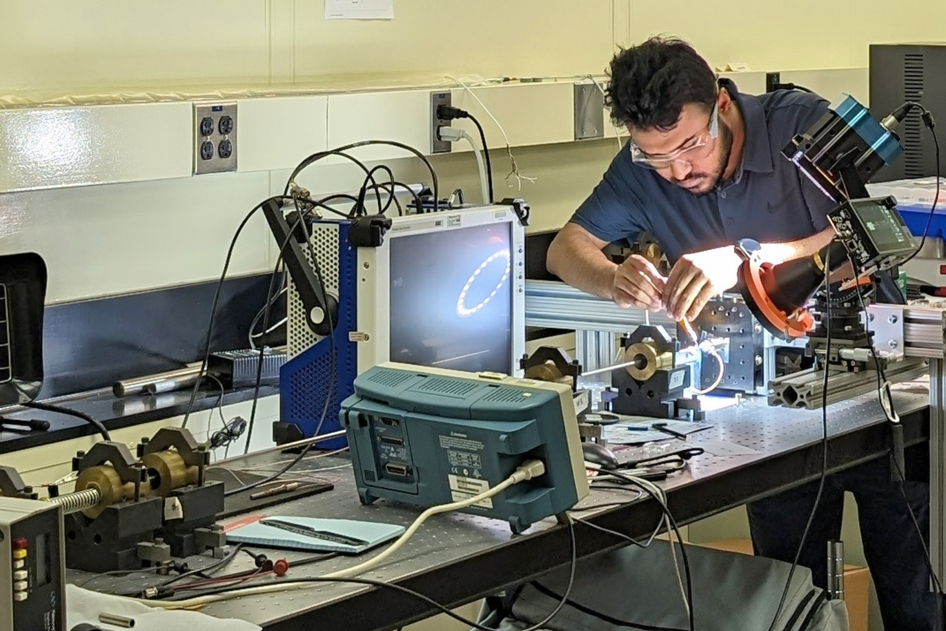 A Ph.D. student wearing safety glasses and working in an engineering lab.
