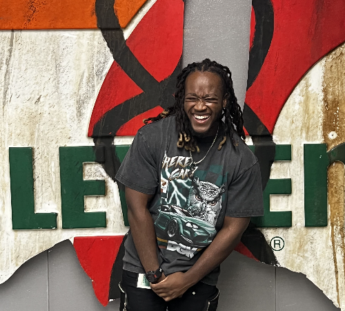 Joshua Michaels standing in front of 7-Eleven sign smiling