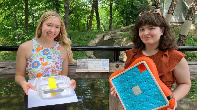 two psychology students studying animal behavior at the zoo