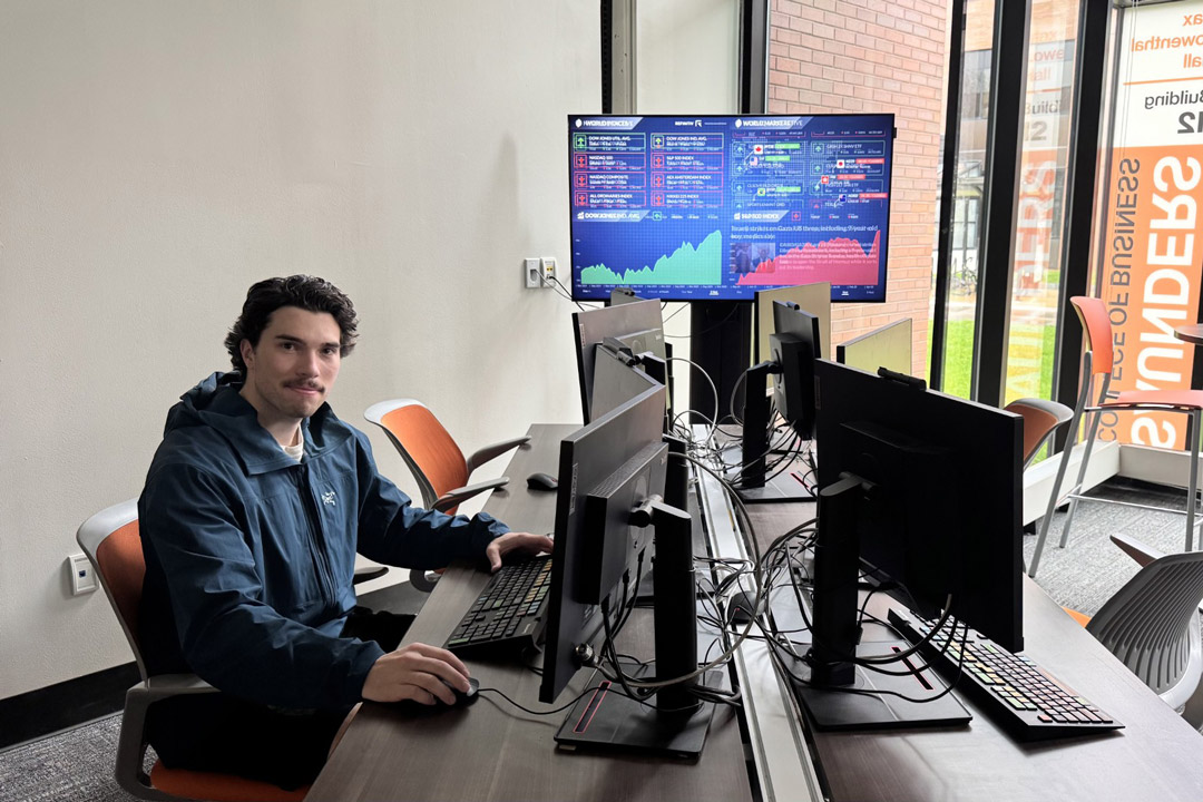 Student sitting in front of computers smiling