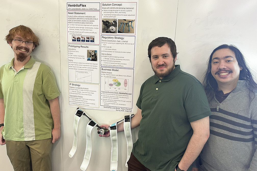 Three RIT Master's students standing on either side of a research poster and smiling.