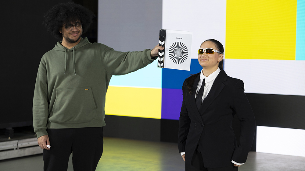 Two students stand in front of a giant LED virtual production screen.