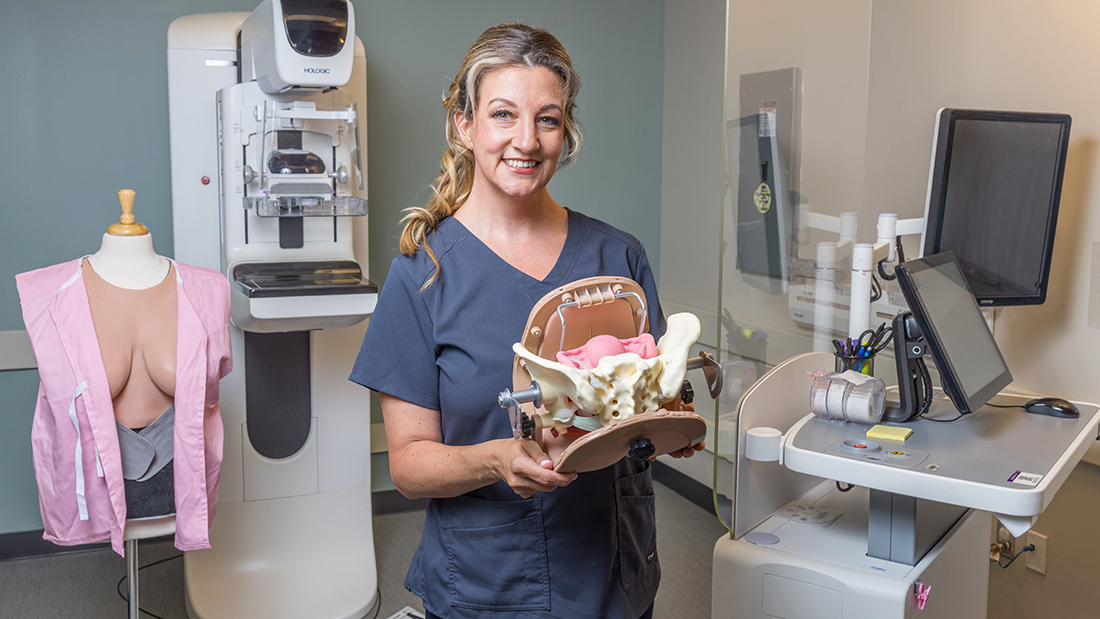 Erica McCarthy poses with a mammography tool she helped develop.