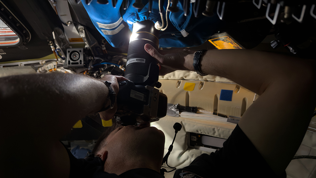An astronaut operates a camera in a spaceship.