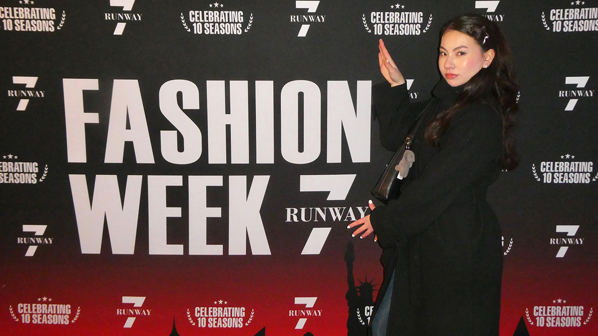 Shannon Lesch stands in front of a Fashion Week banner.