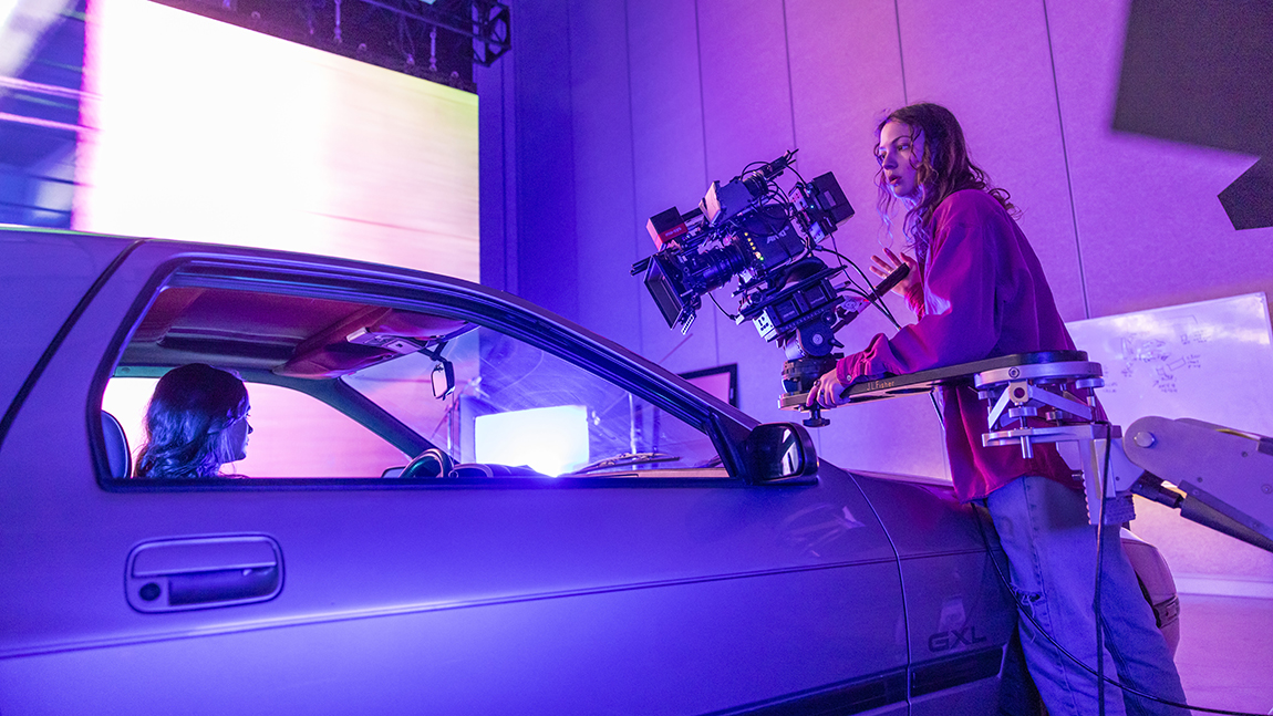 A student films a car on a virtual production stage.