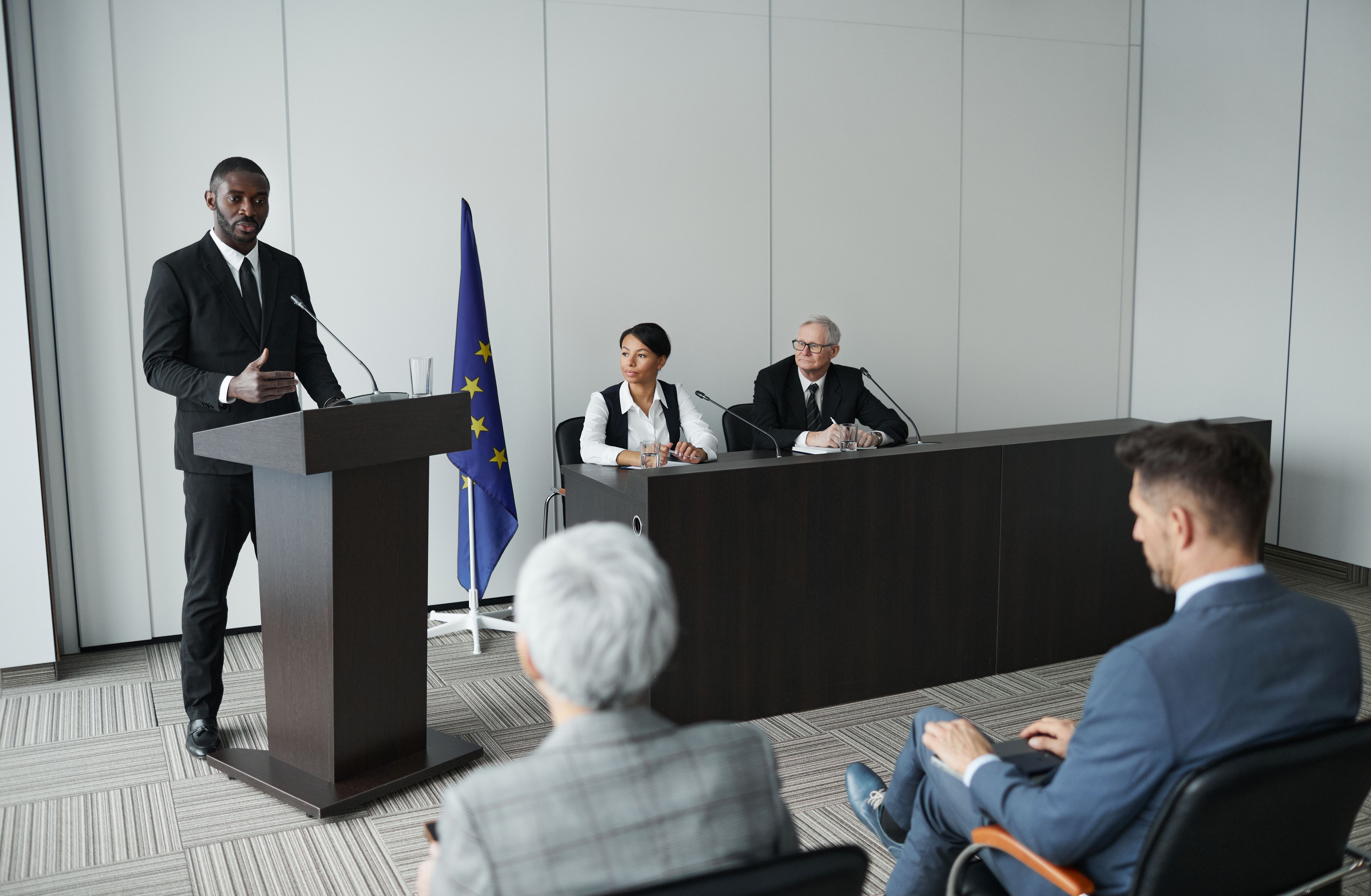 person standing in the front of a room of people at a podium