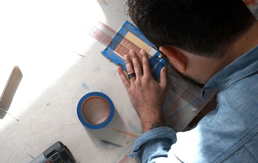 overhead view of a person cutting paper along a ruler with an Exacto knife.