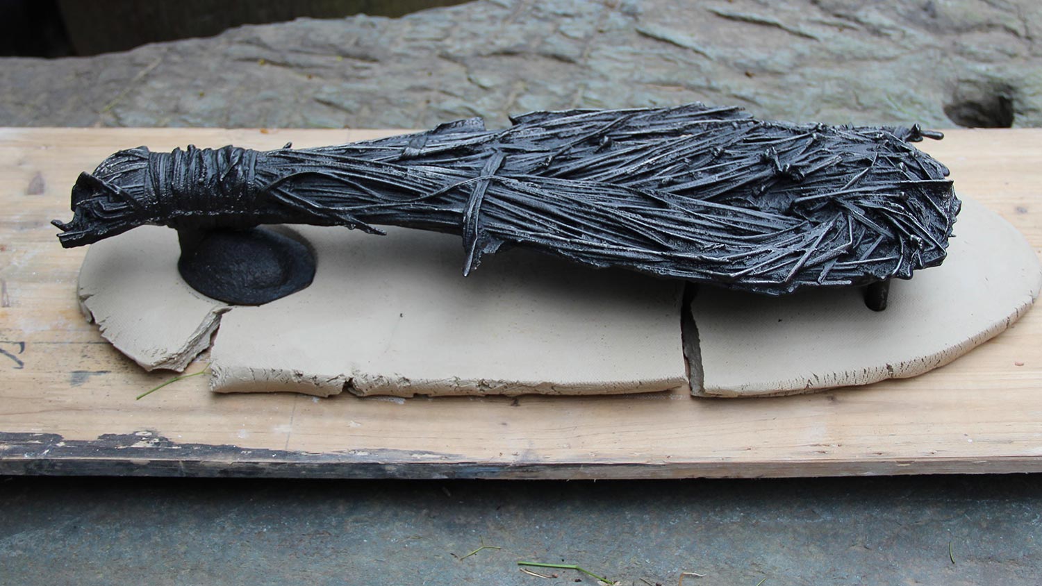 a cast iron sculpture that resembles a small hearth broom.