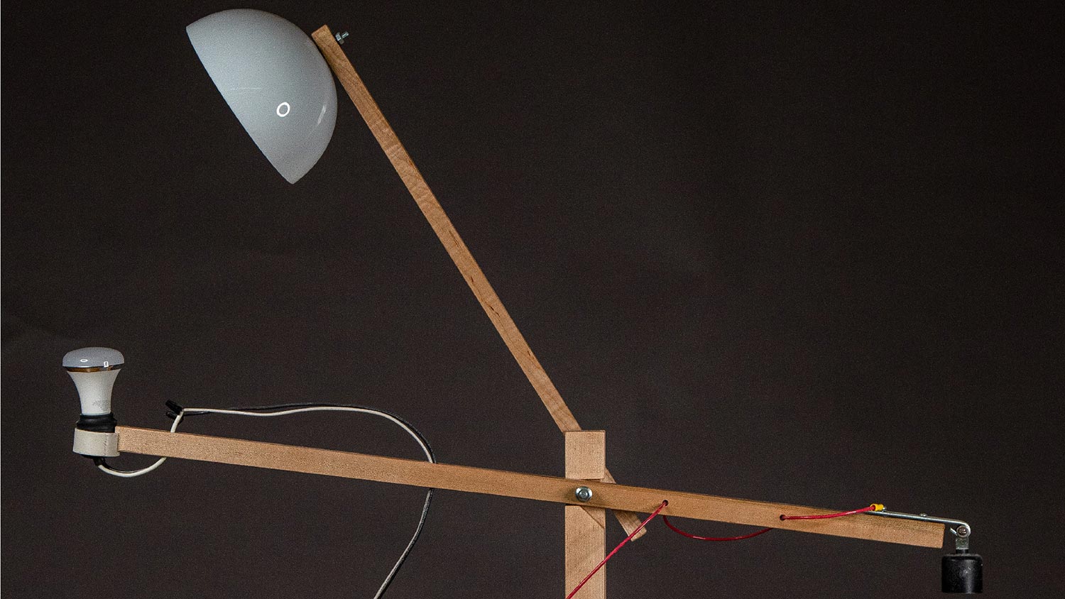 Lamp made from two arms like a scissors, with the lampshade on one arm and lightbulb on the other.