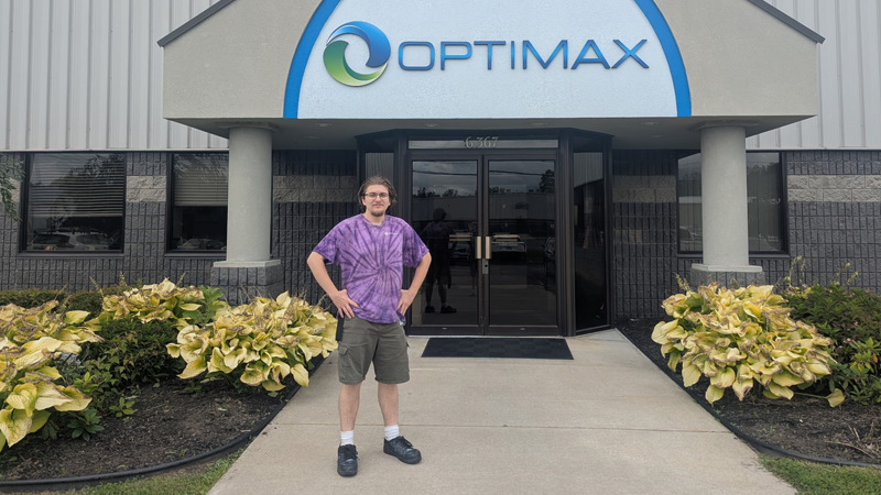 Joey Root standing in front of the Optimax building