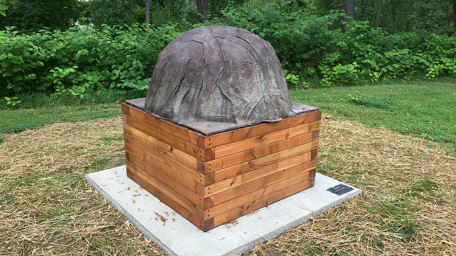 a half-circle sculpture outdoors on a wooden box.