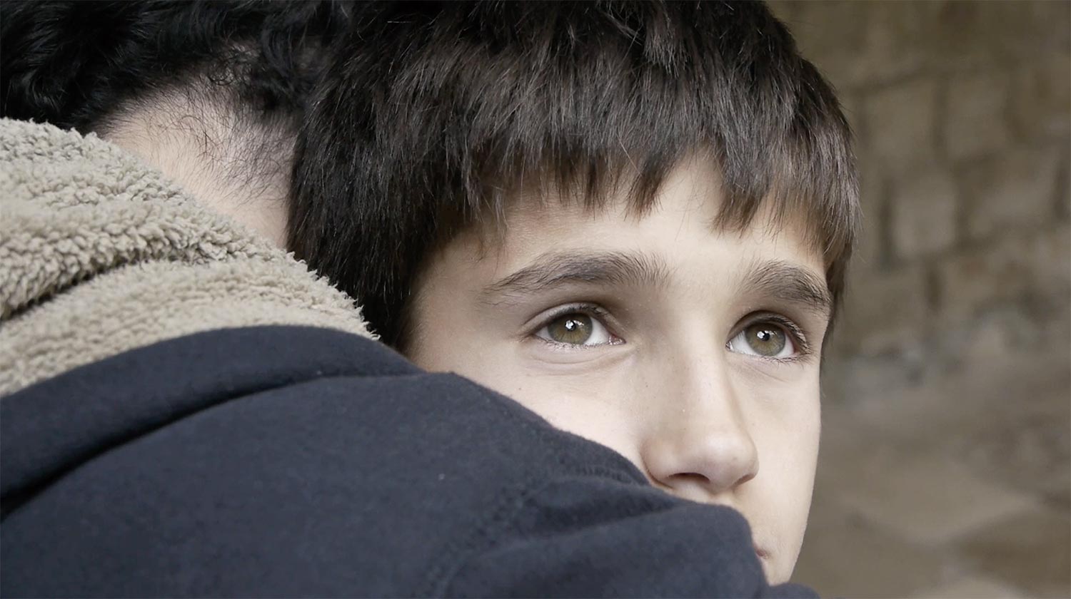 close up of a child hugging another person.