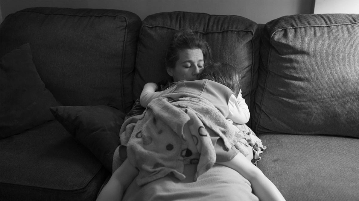 black and white photo of a child lounging on a mom on a couch.