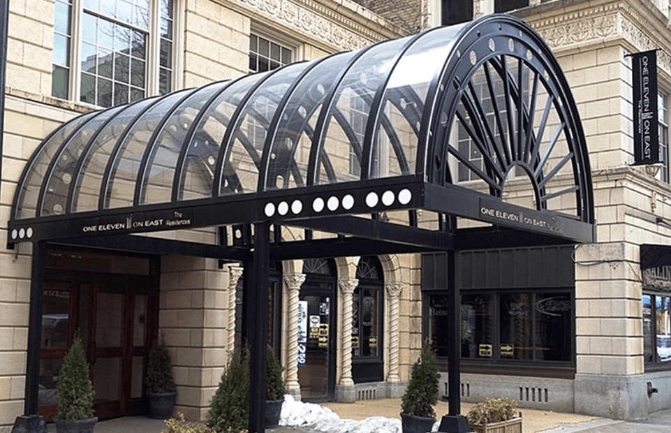 a rounded, glass covered entry canopy for a building in a city.