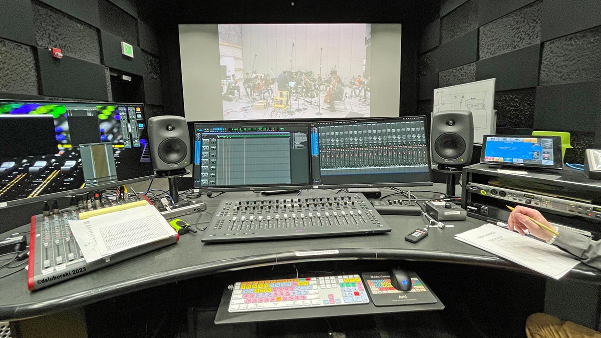 a sound mixing studio with several computer monitors, speakers, and sound adjusting equipment.