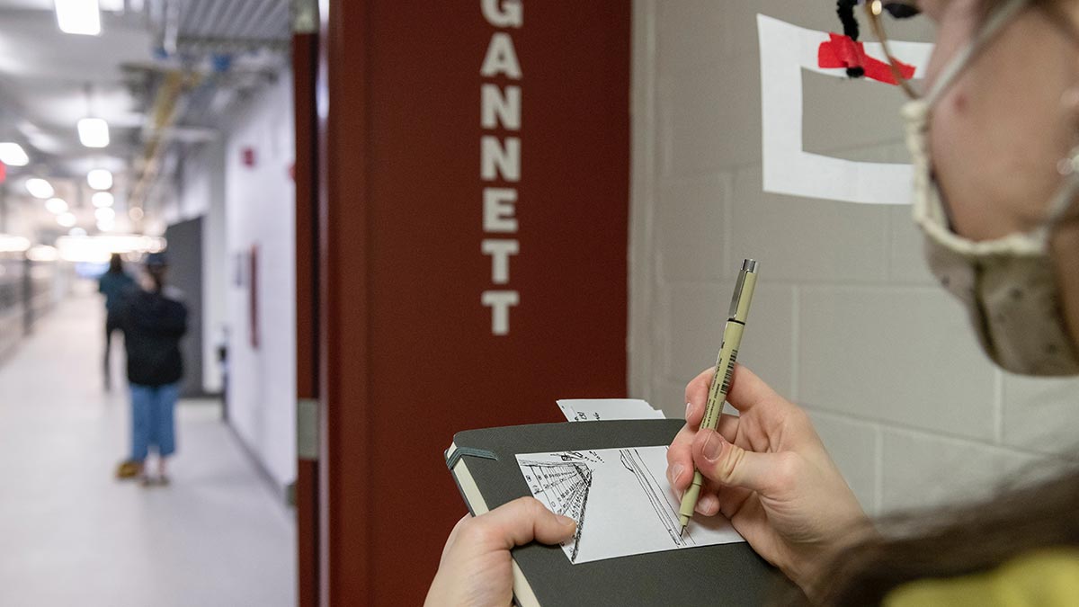 a student making a sketch of a hallway in a college.
