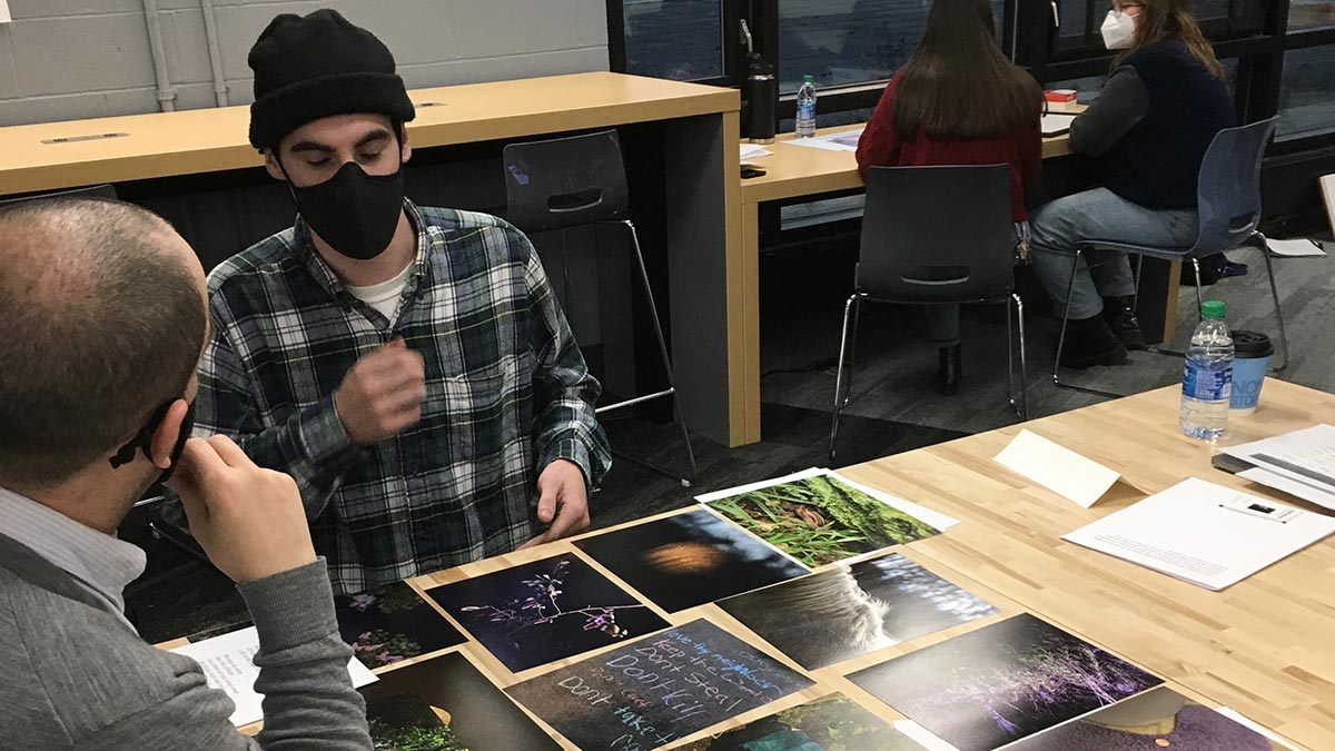 student and reviewer sit at a table with several images displayed.