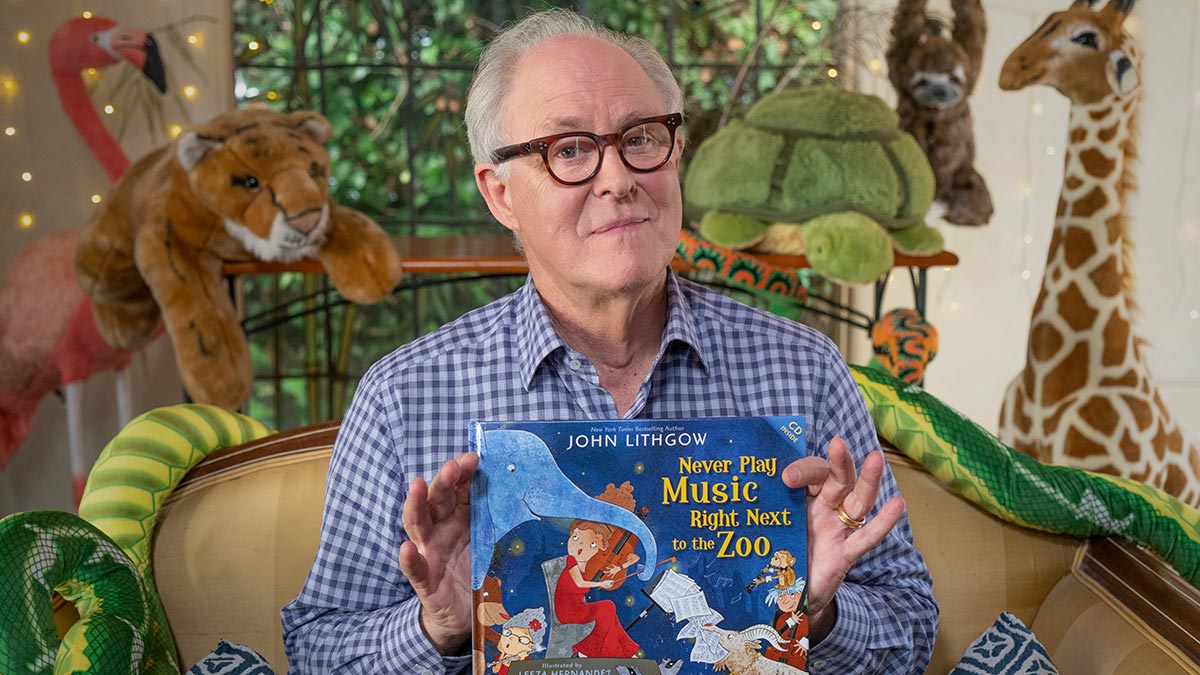 Actor John Lithgow holds a book called Never play music right next to the zoo.