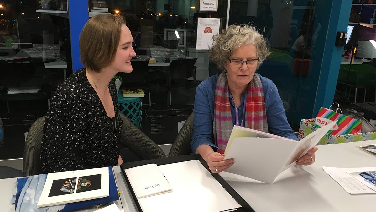 reviewer looks at student's art portfolio.